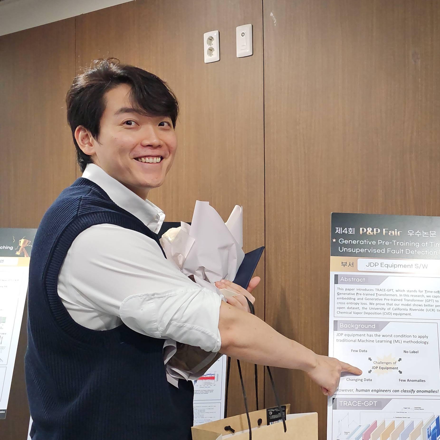 Sewoong holding a bouquet beside his research poster at the Samsung P&P Fair.